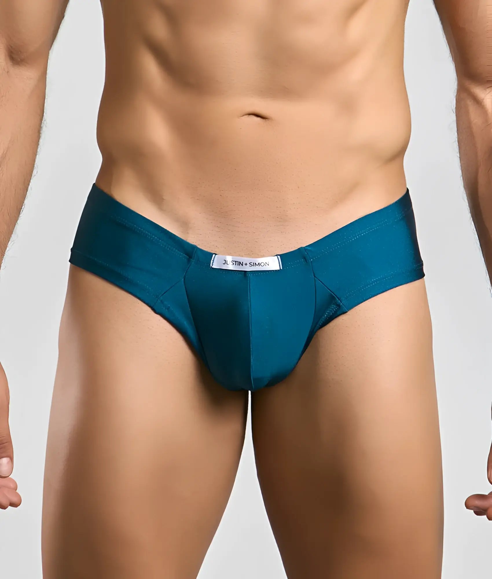 Teal-colored form-fitting briefs in smooth fabric with a white Justin + Simon brand tag at the waistband