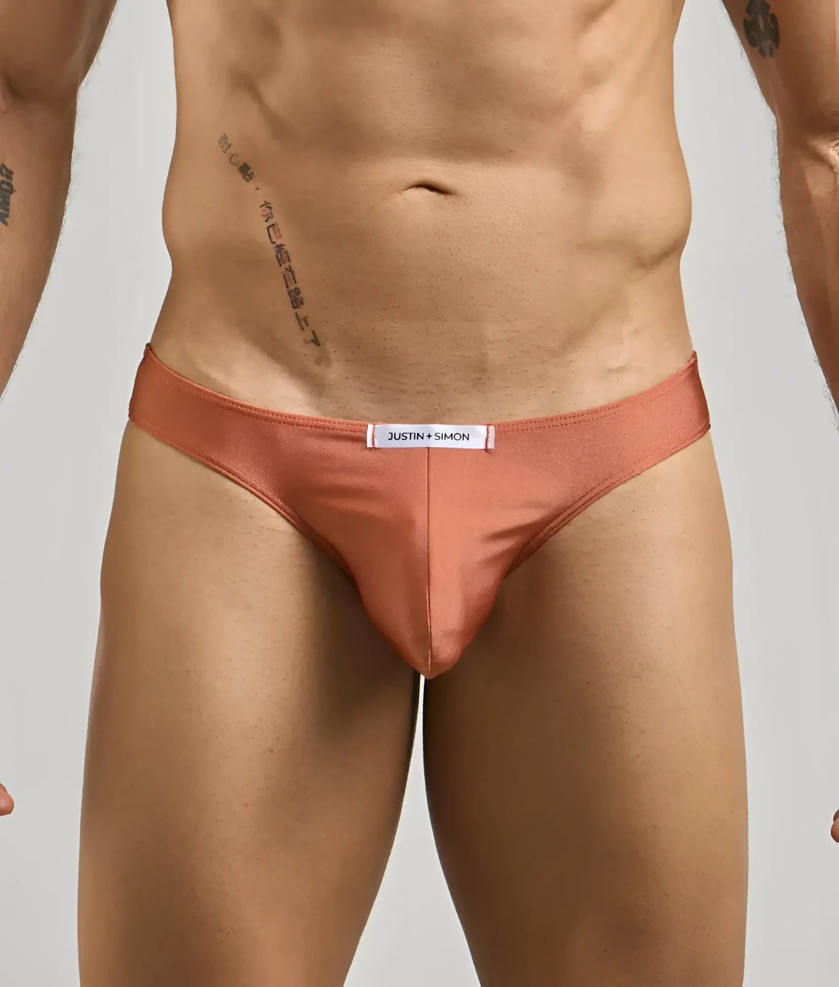 Coral-colored satin briefs with a white justin + simon label at the waistband from the classic mens bikini collection