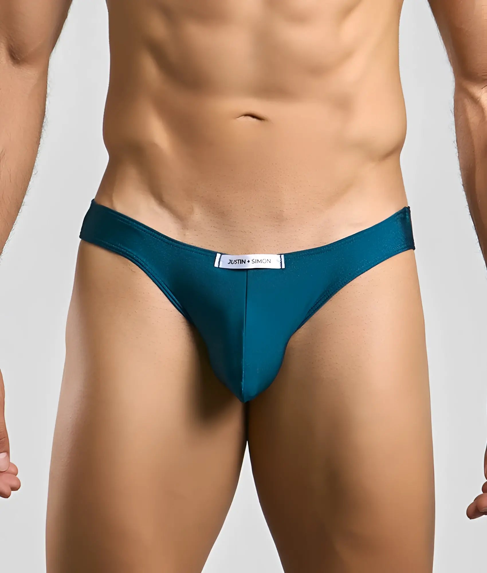 Teal form-fitting briefs with sleek smooth fabric and a white justin + simon label at the waistband classic mens bikini