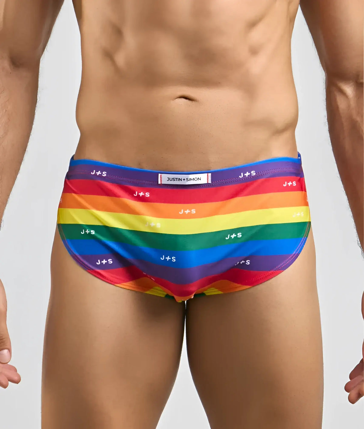 Justin simon running short rainbow-striped men’s swim trunks with vibrant spectrum and repeating j plus s branding
