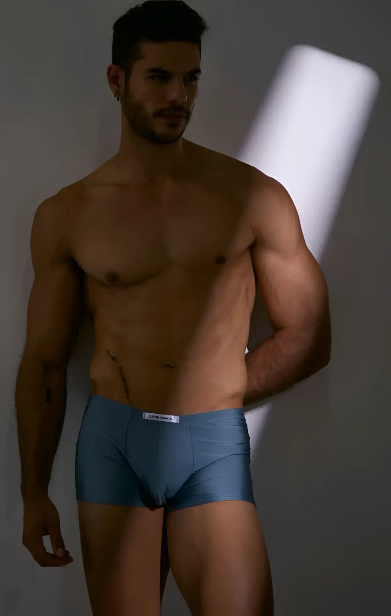 Blue men’s boxer briefs with a white waistband featuring the Justin+Simon brand label in classic metal green color