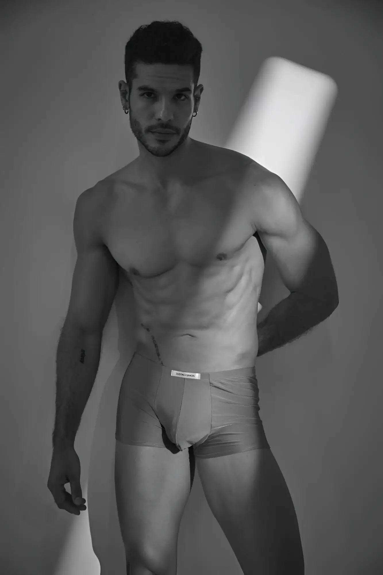 A man wearing light-colored form-fitting Calvin Klein underwear with a visible logo on the waistband in metal green color