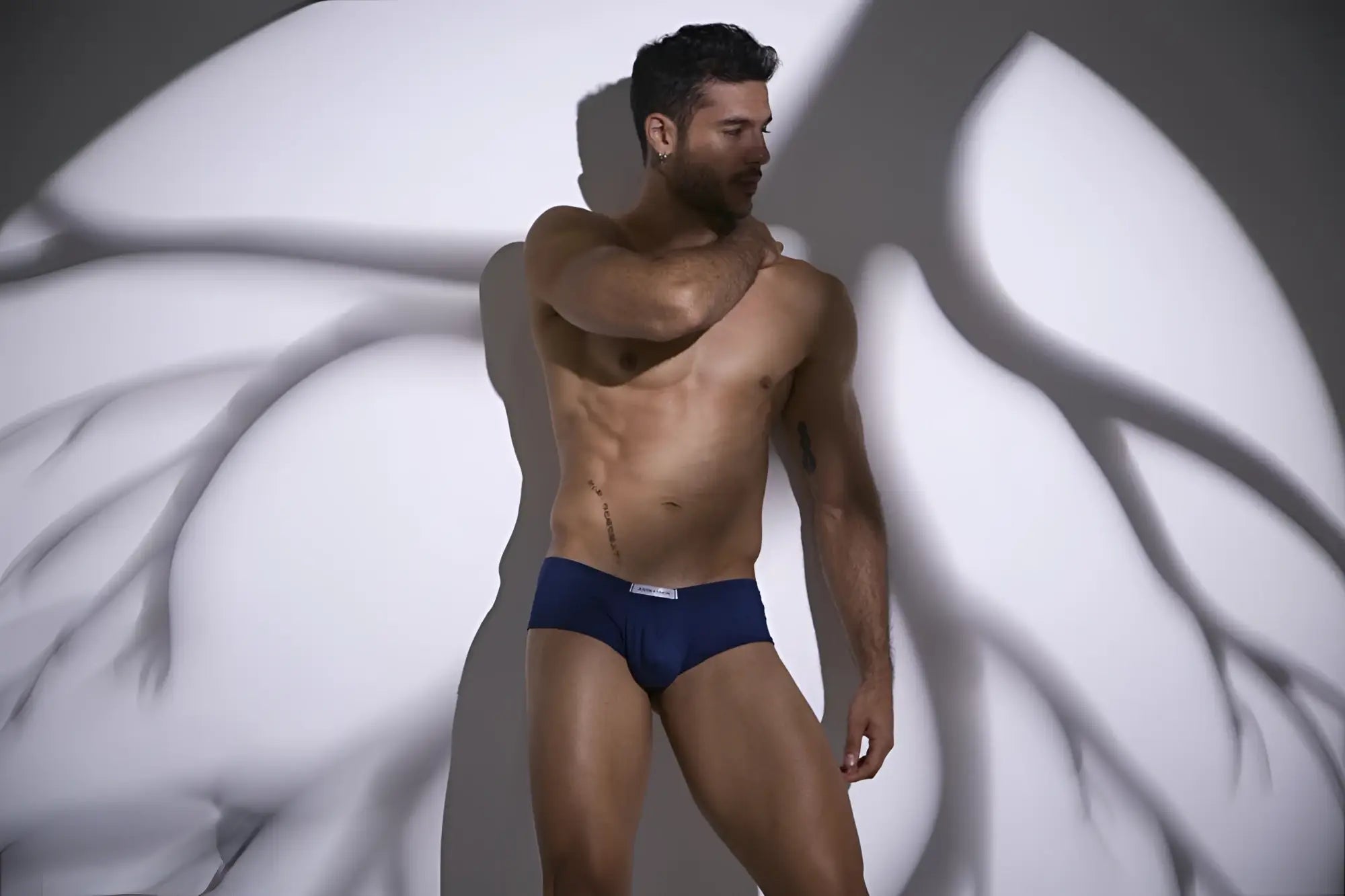 Navy blue cheeky bulge boxer briefs with a white logo waistband from Justin Simon in peach and navy colors