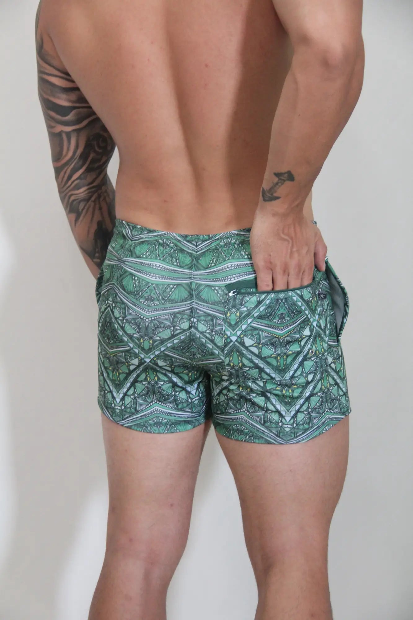 Kaleidoscope shorts green patterned swim trunks with teal white and dark green geometric and tribal-inspired designs