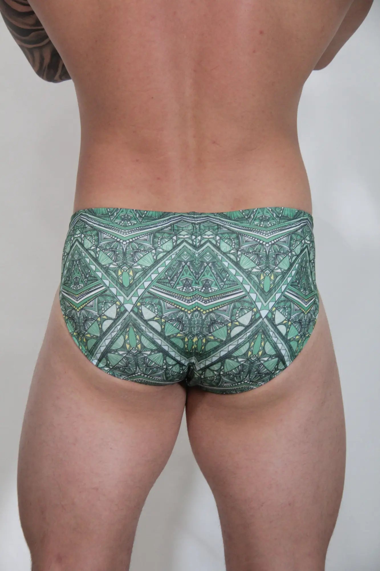 Kaleidoscope swim brief featuring green patterned swim trunks with geometric and tribal-inspired designs