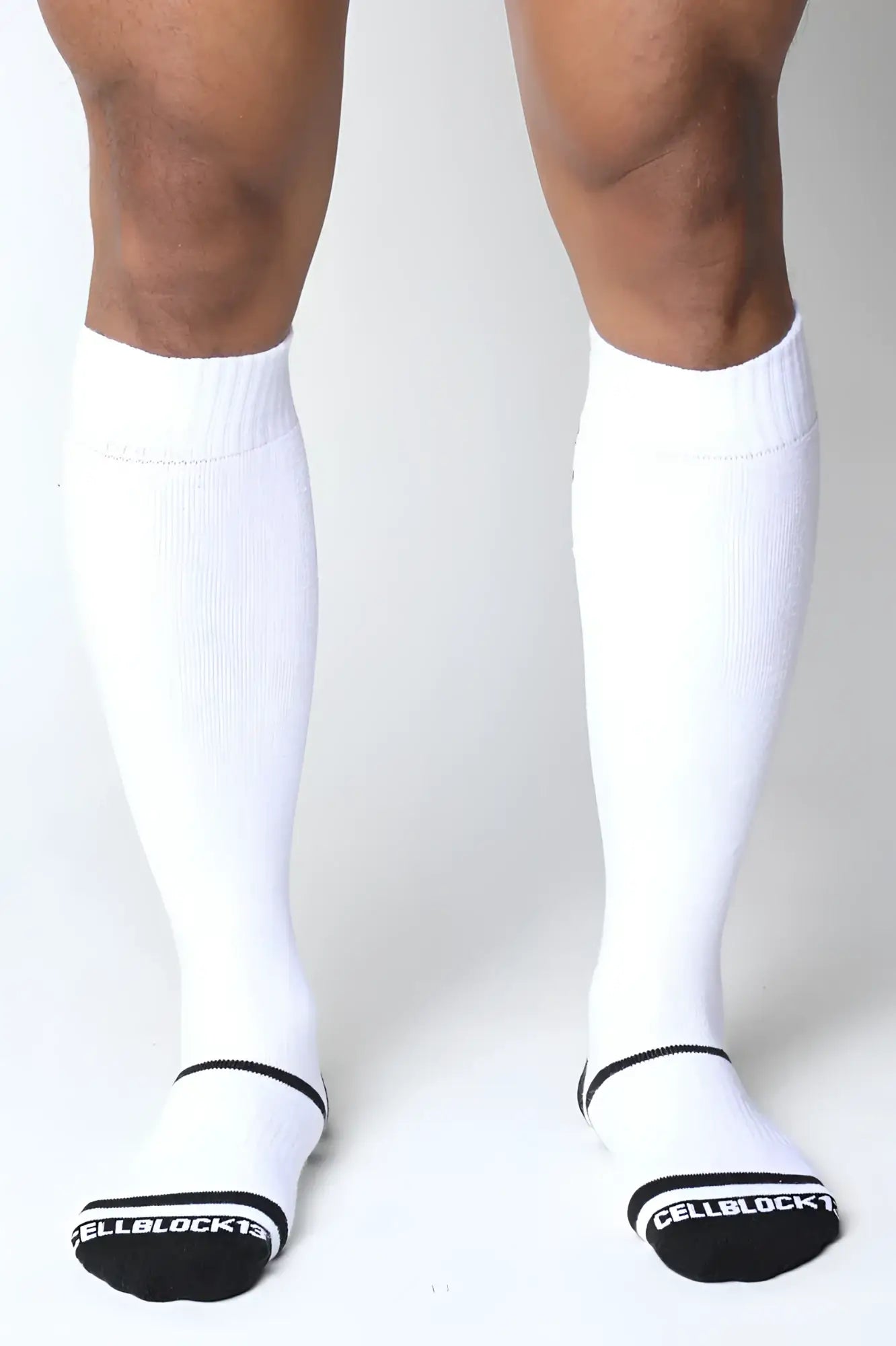 White knee high socks with black trim and ribbed texture featuring cellblock 13 branding on the heel back side
