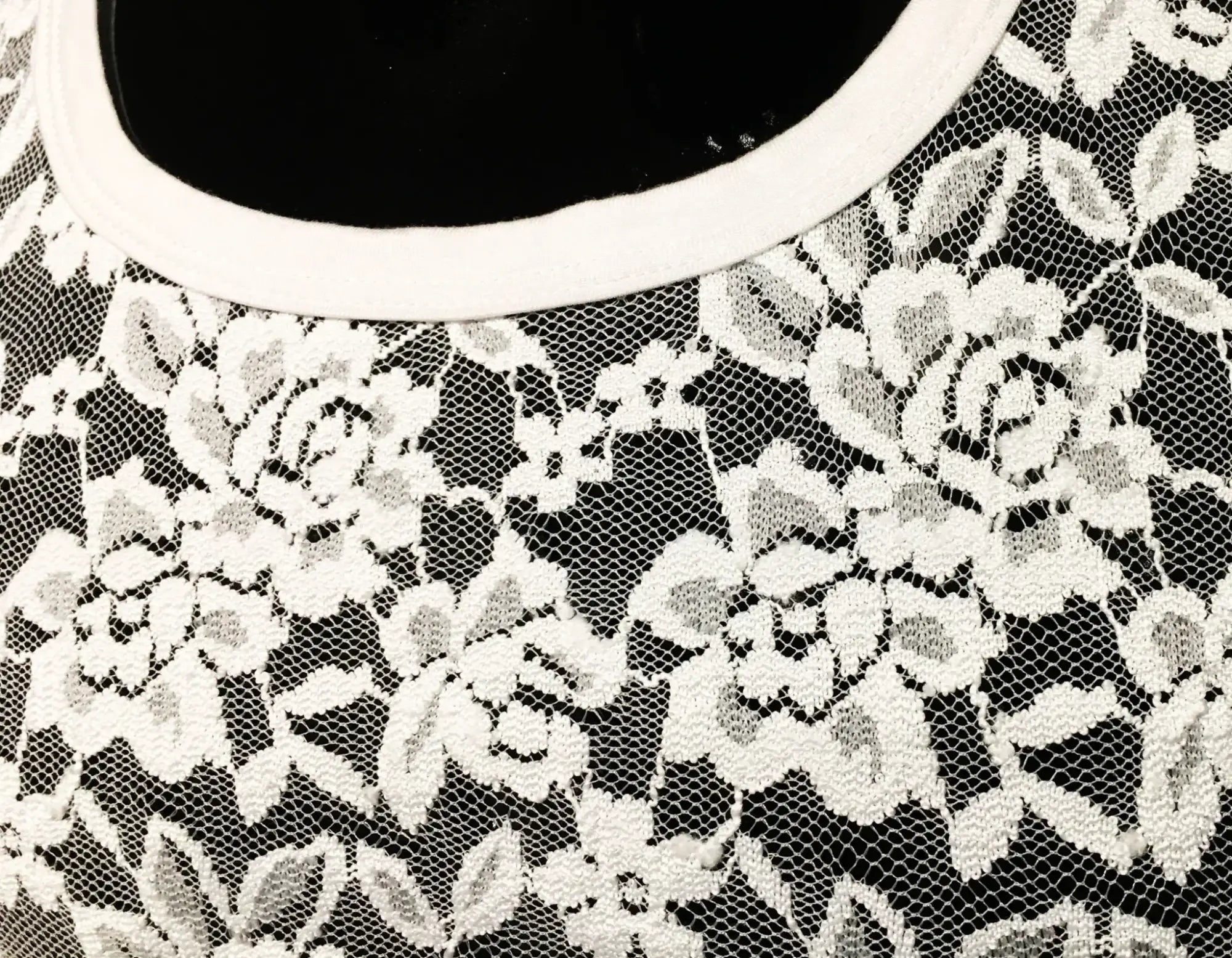 White floral lace tee with black base and rounded white neckline showcasing delicate lace detail on front