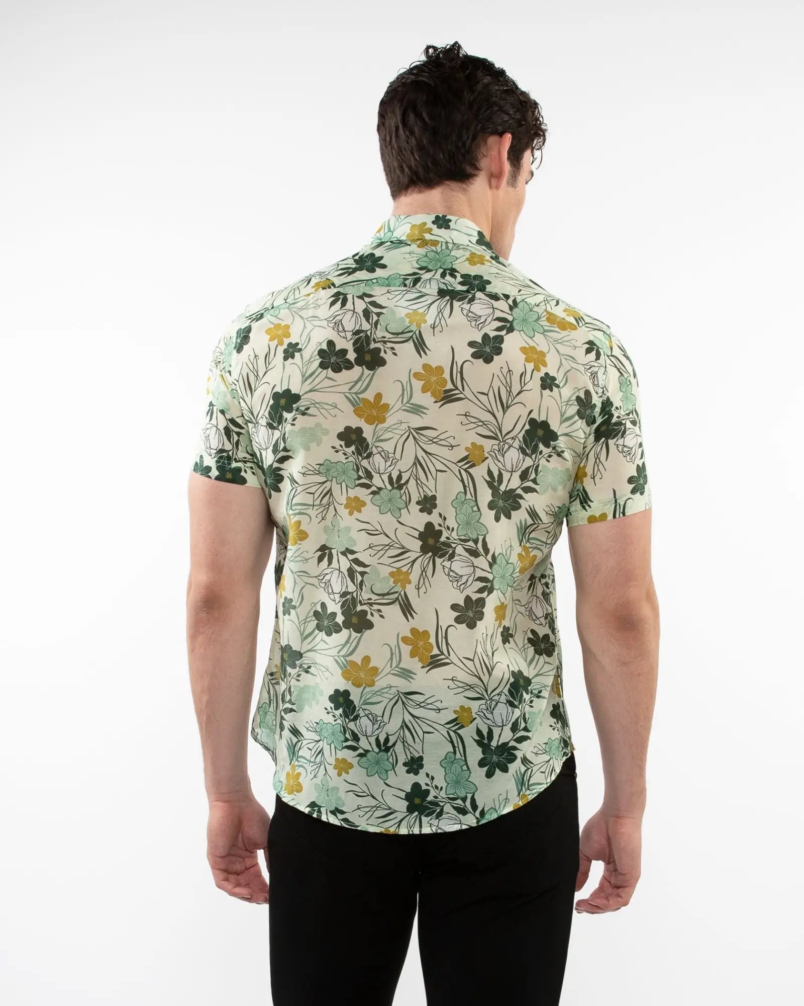 A man wearing a lightweight cotton silk short-sleeved shirt with green yellow floral pattern on off-white background
