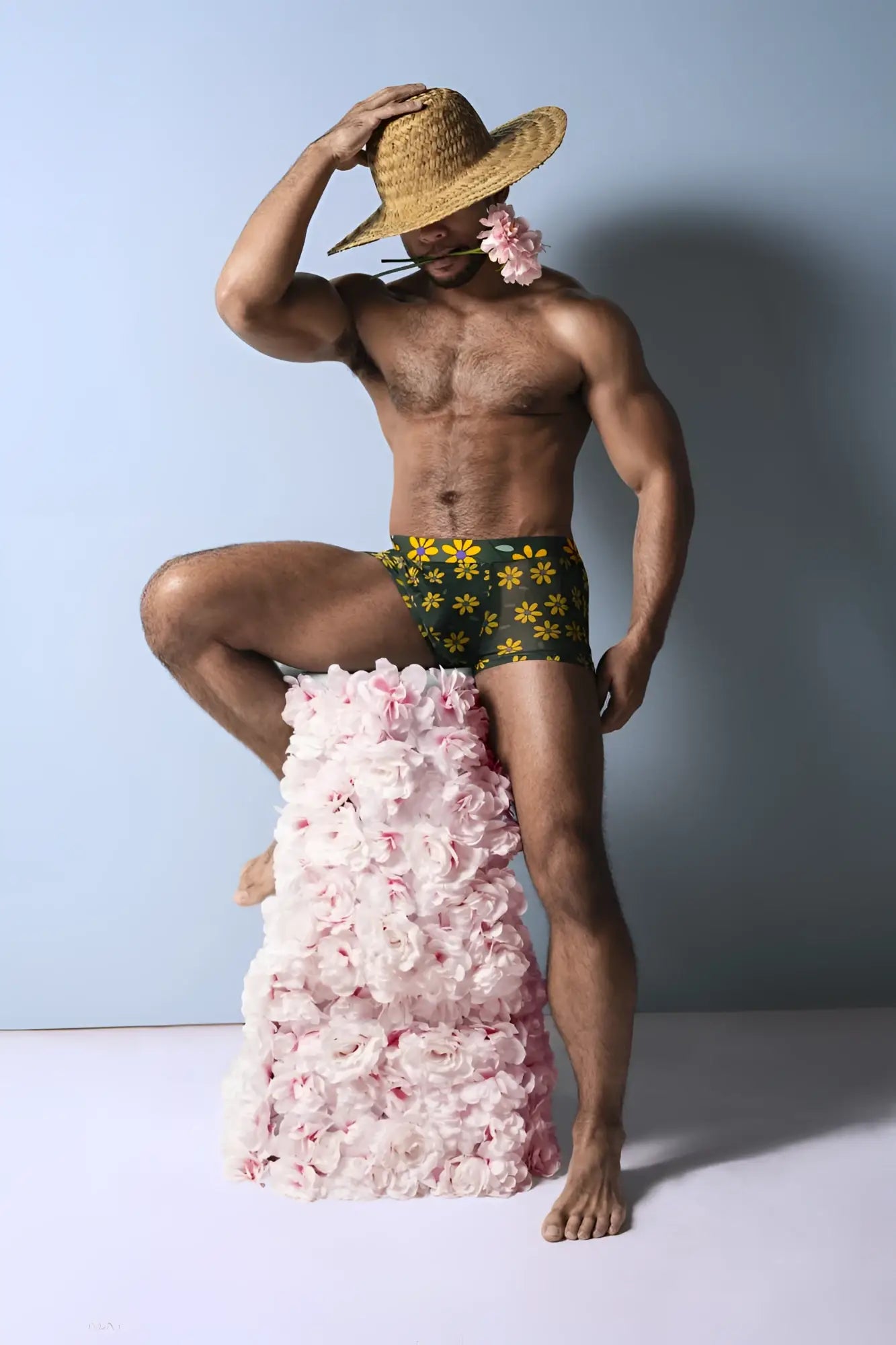 A man wearing male power petal power pouch shorts in green and yellow daisy print floral swim trunks