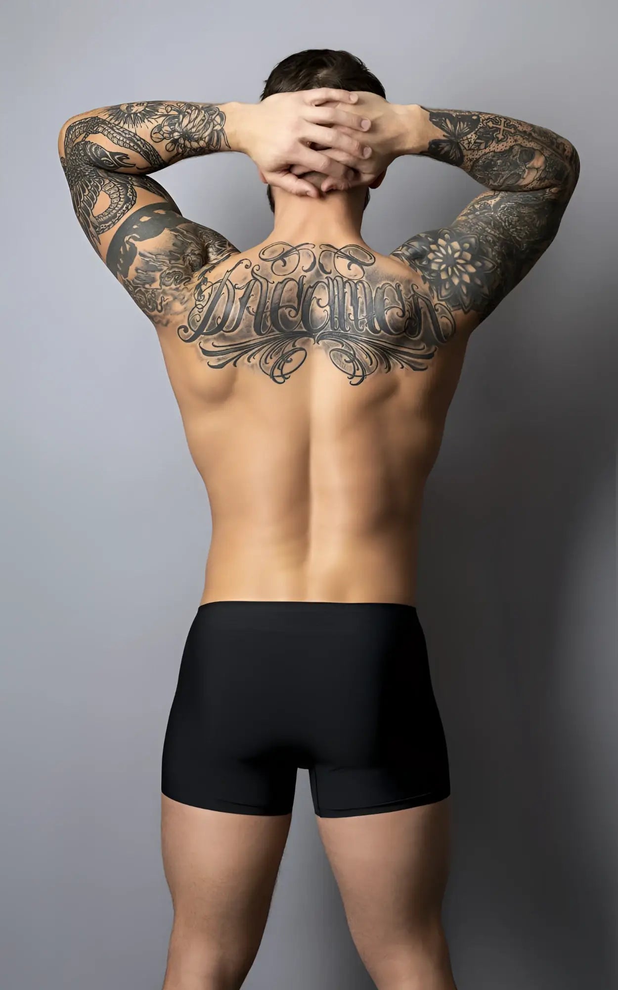 A man wearing male power 154-300 hot mesh pouch short black-red shows tattooed back and arms from the rear side