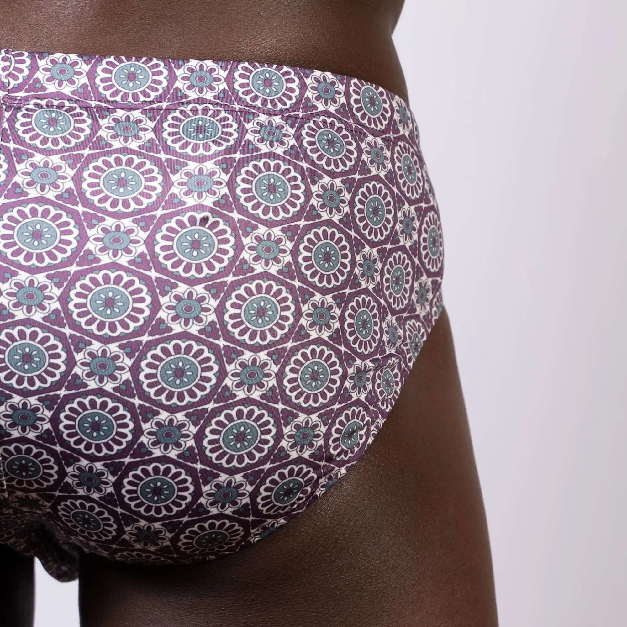 Mandala swim brief in purple and teal with floral and geometric pattern designed for stylish swimwear use