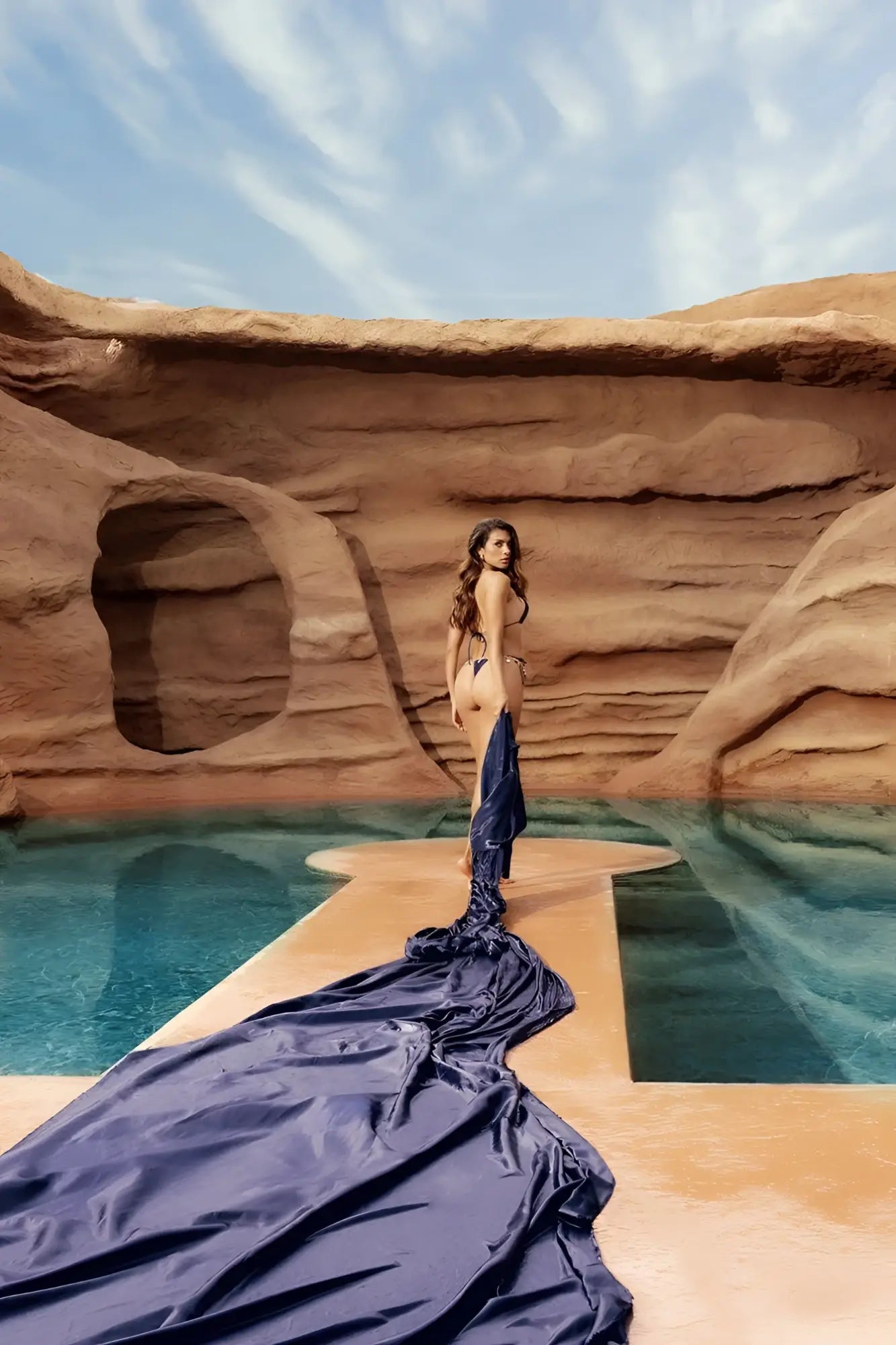 A deep ocean two piece swimsuit by mapale draped with flowing navy blue satin fabric by the poolside
