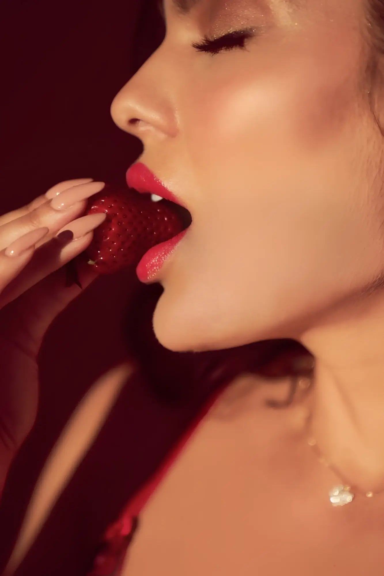 A woman with glossy red lips bites a ripe strawberry wearing the mapale 8899 black-red two piece set