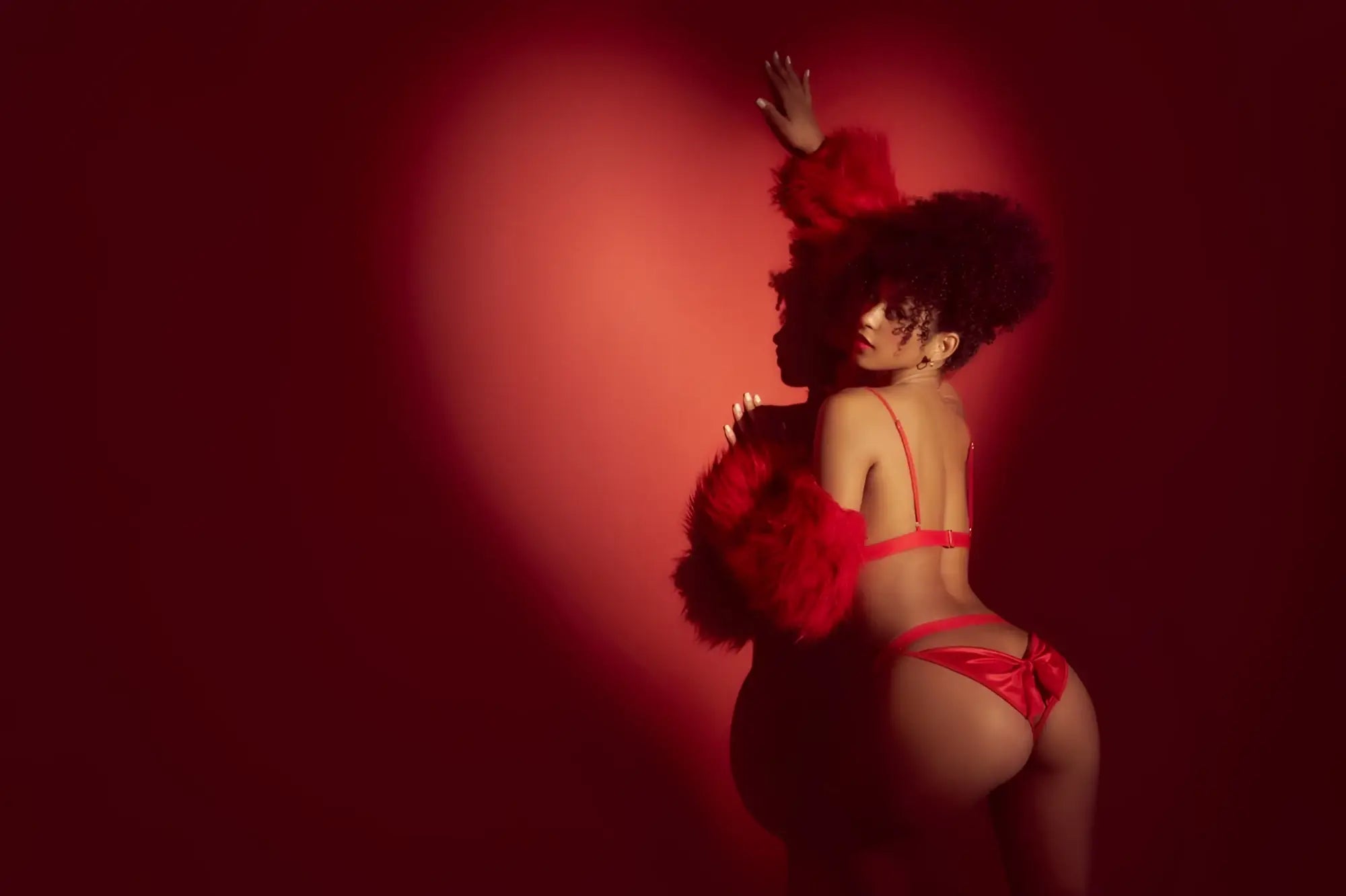A woman wearing the mapale 8901 two piece set in shiny red satin lingerie with matching feathered shoulder accents