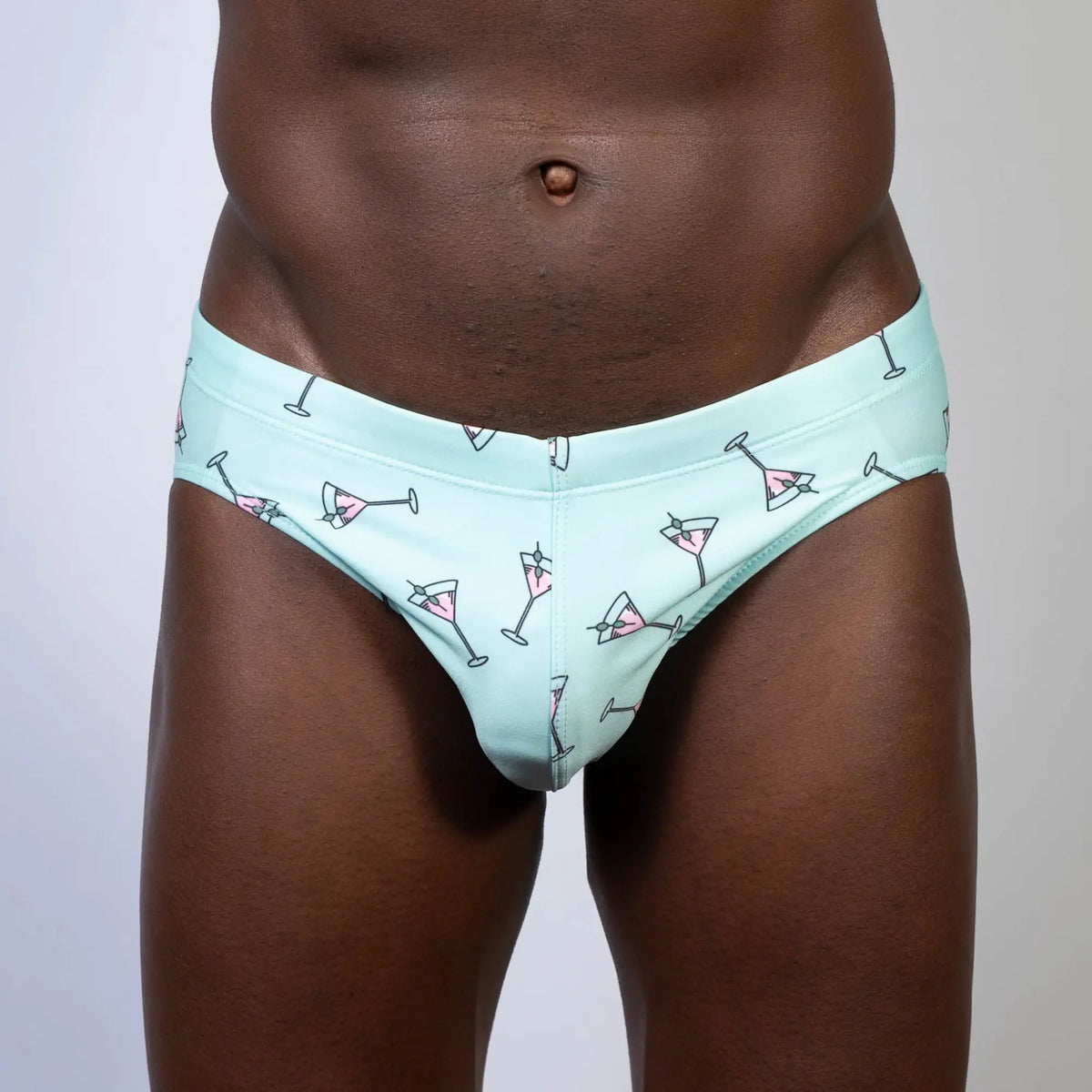 Mint green martini swim brief with playful pink martini glass pattern and black outlines for swimwear use