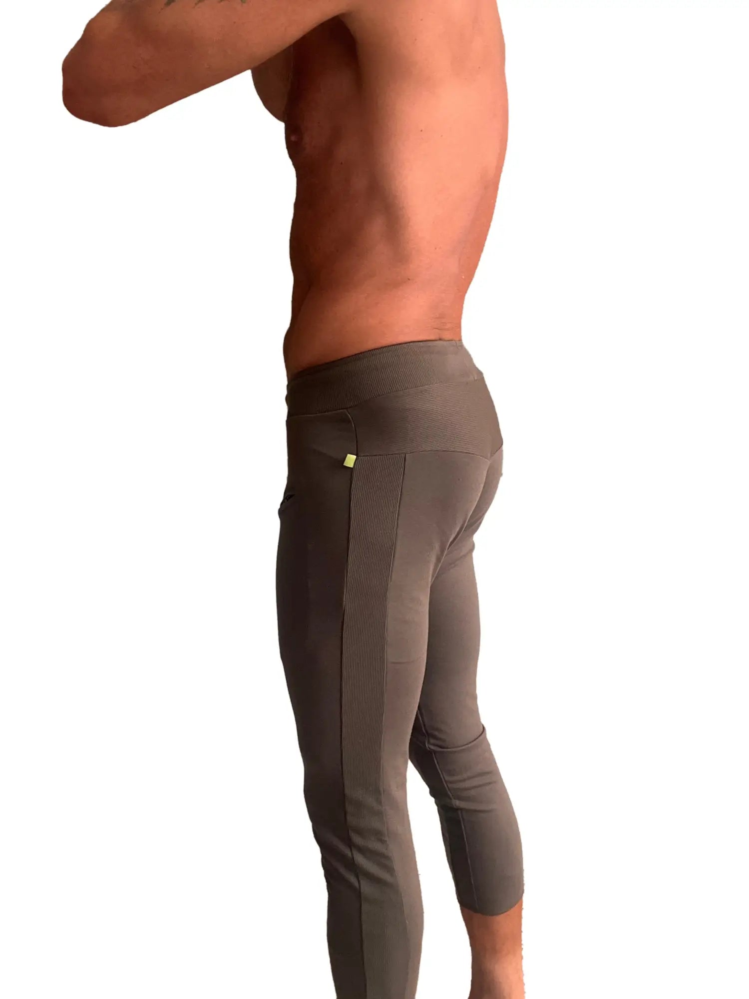 Back view of mens dark gray form fitting capri yoga pants with textured side panel and yellow tag on pocket
