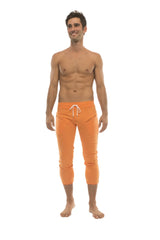 Mens 4/5 zipper pocket capri yoga pants in solid orange with white drawstring waistband for athletic use