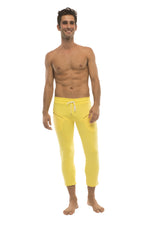 Mens solid yellow capri yoga pants with white drawstring waistband and side pockets for athletic use
