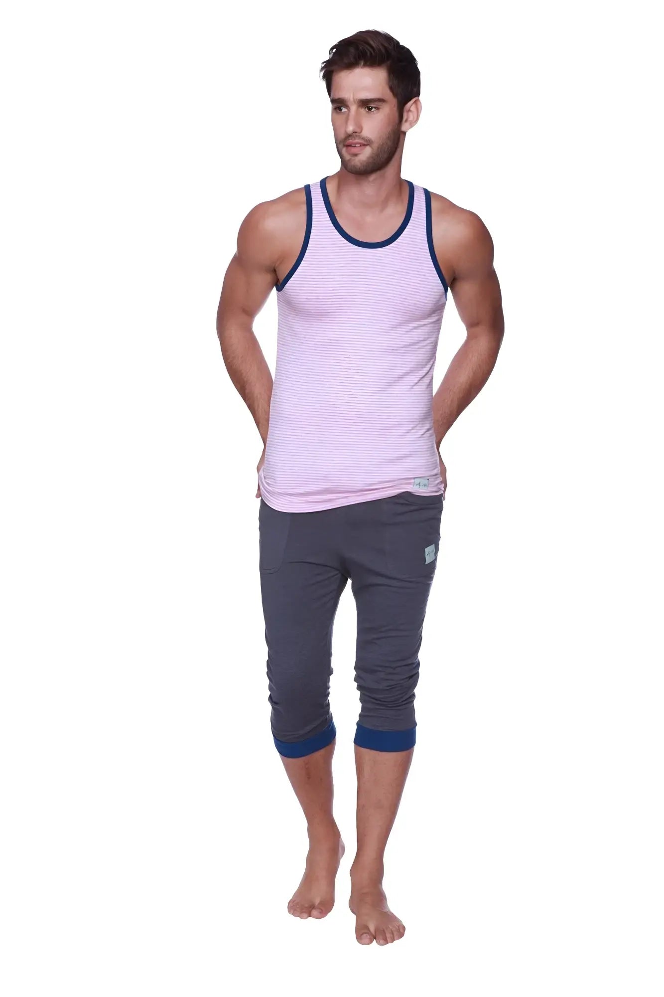 A man wearing mens cuffed yoga pants in charcoal with royal blue cuffs and a light pink striped tank top