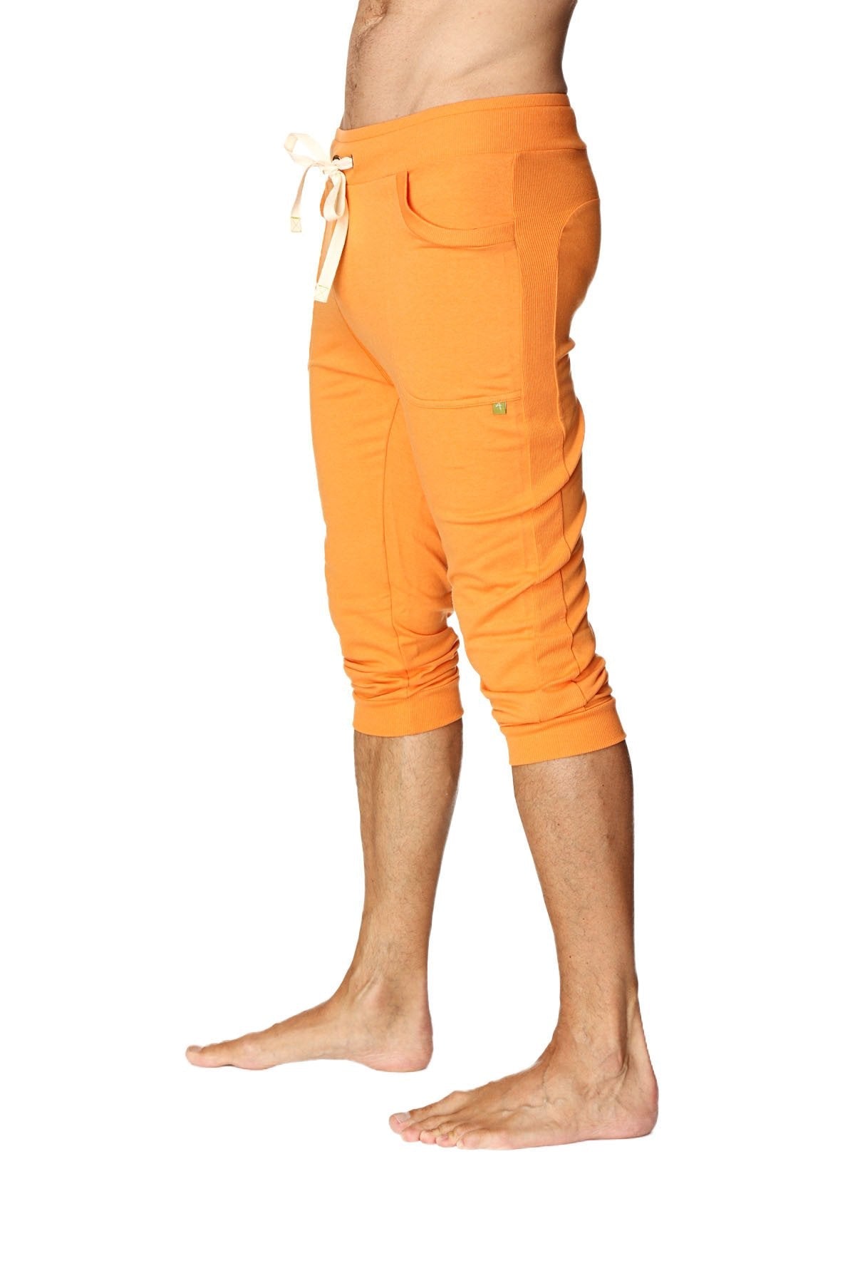 Mens cuffed yoga pants in solid sun orange with white drawstring waistband and multiple pockets made from soft fabric