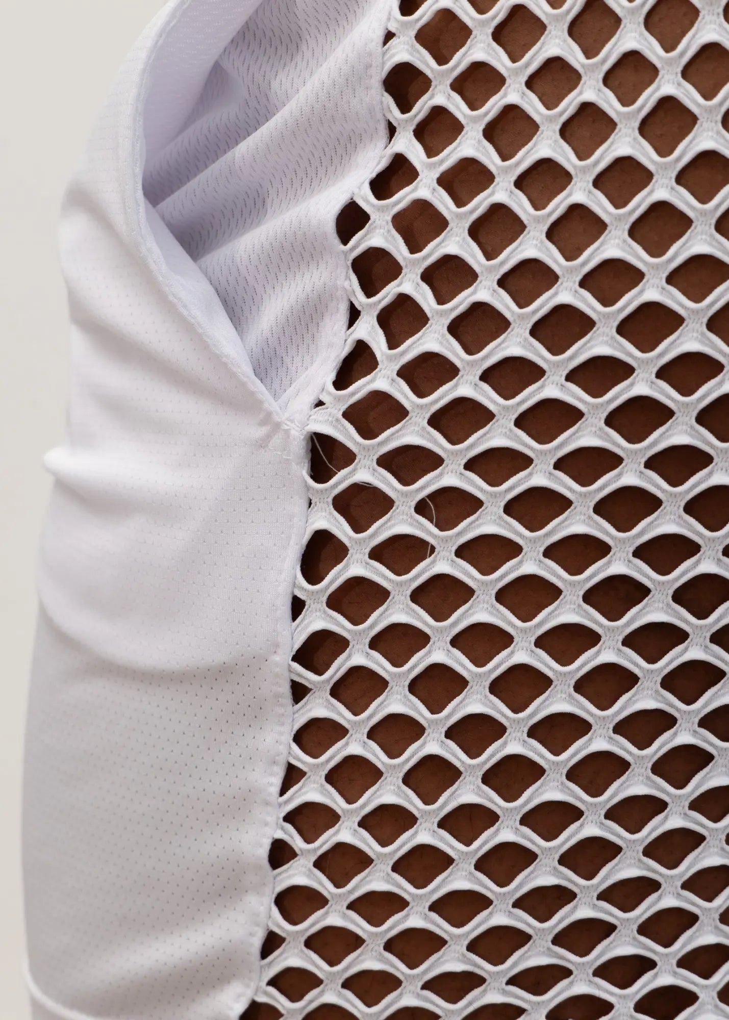 White mesh athletic vest with breathable diamond pattern and solid fabric arm panel shown from the back in mesh back short product