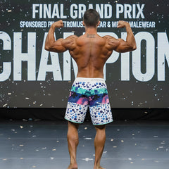 A man wearing vibrant metro male wear metro musclewear bubble physique board shorts with colorful abstract designs