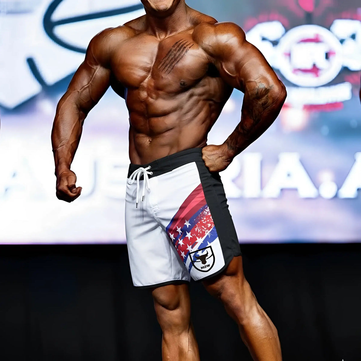 White and black MetroMuscleWear IFBB Pro mens physique board shorts with red white and blue star stripe and black bull logo
