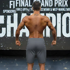 Gray charcoal MetroMaleWear MetroMuscleWear Insignia Physique athletic board shorts worn by a muscular man