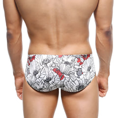 White swim trunks by metromalewear featuring a bold black and red floral poppy pattern for beachwear
