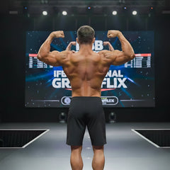 A muscular man shows the back side of black MetroMaleWear Physique board shorts with stripe detailing on stage