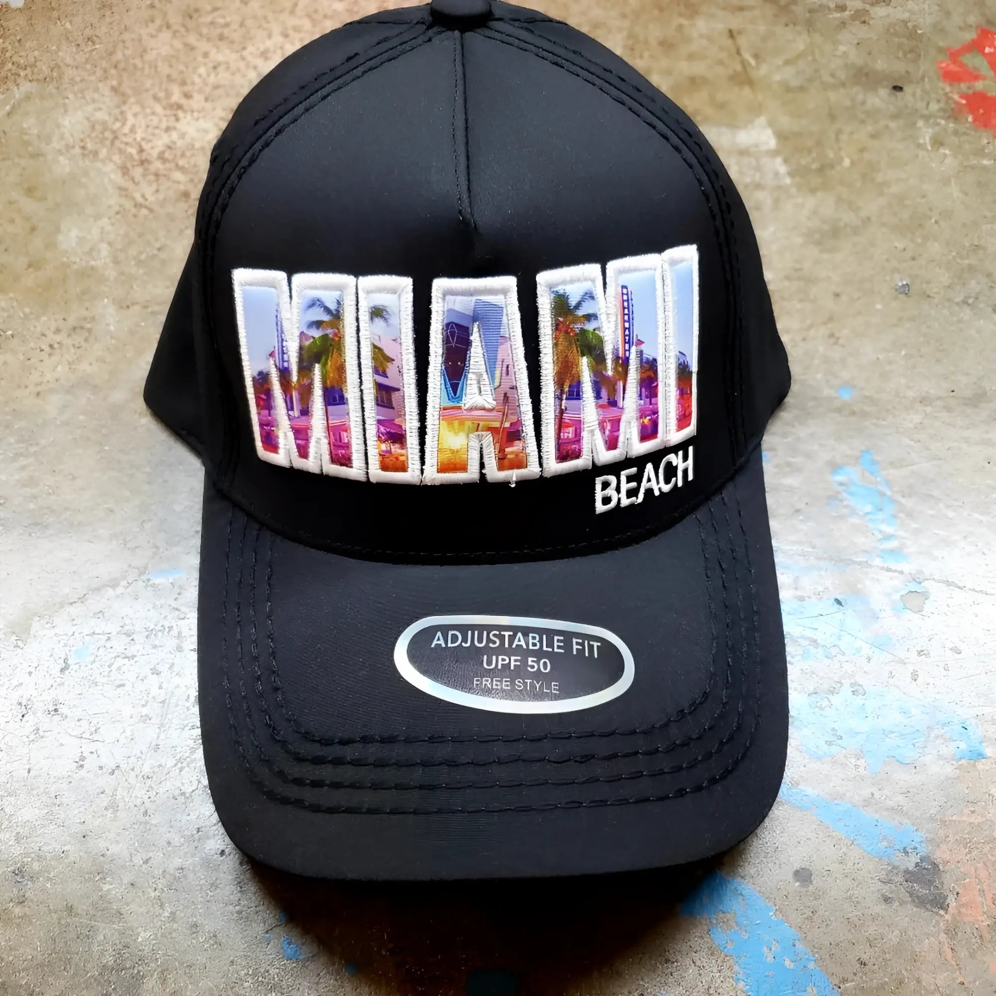 Black trucker hat featuring colorful embroidered miami design with palm trees and cityscape in vibrant hues