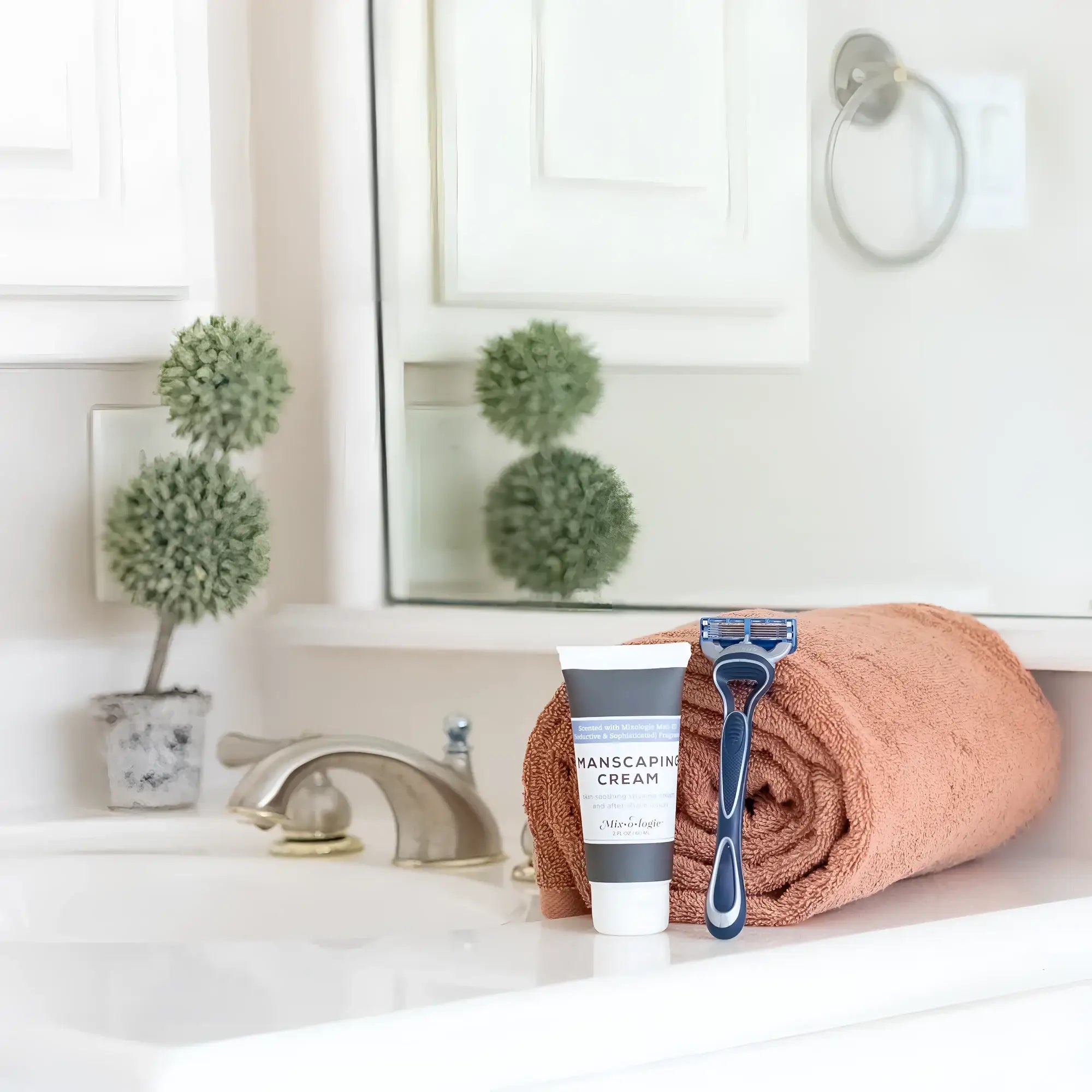 Blue and black five-blade disposable razor resting on a rolled terracotta towel with mixologie manscaping cream shave