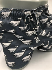 Black swim trunks featuring a repeating white whale pattern with detailed line art from moby dick shorts collection