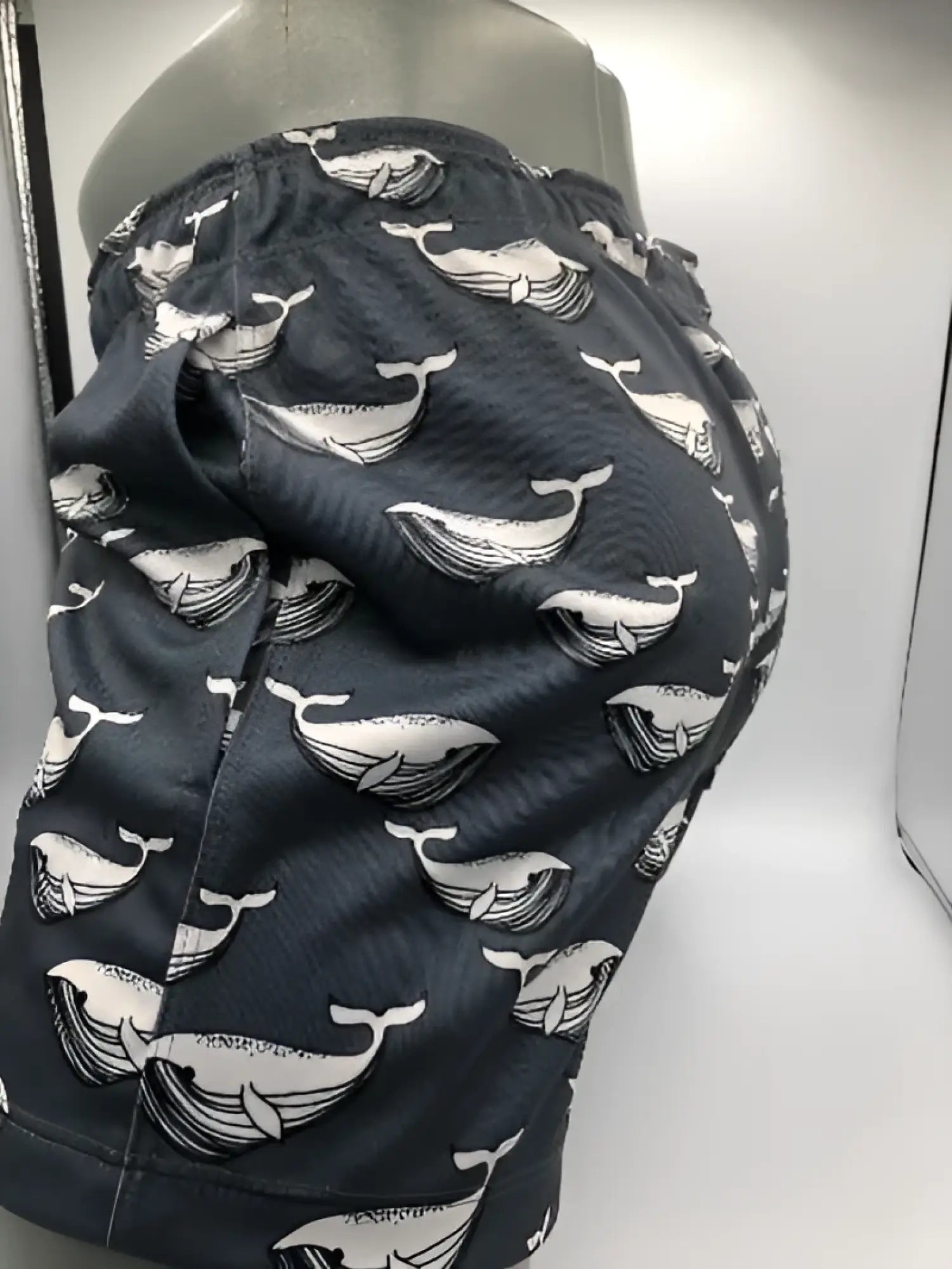 Dark gray moby dick shorts with a repeating white whale pattern swim trunks perfect for beachwear