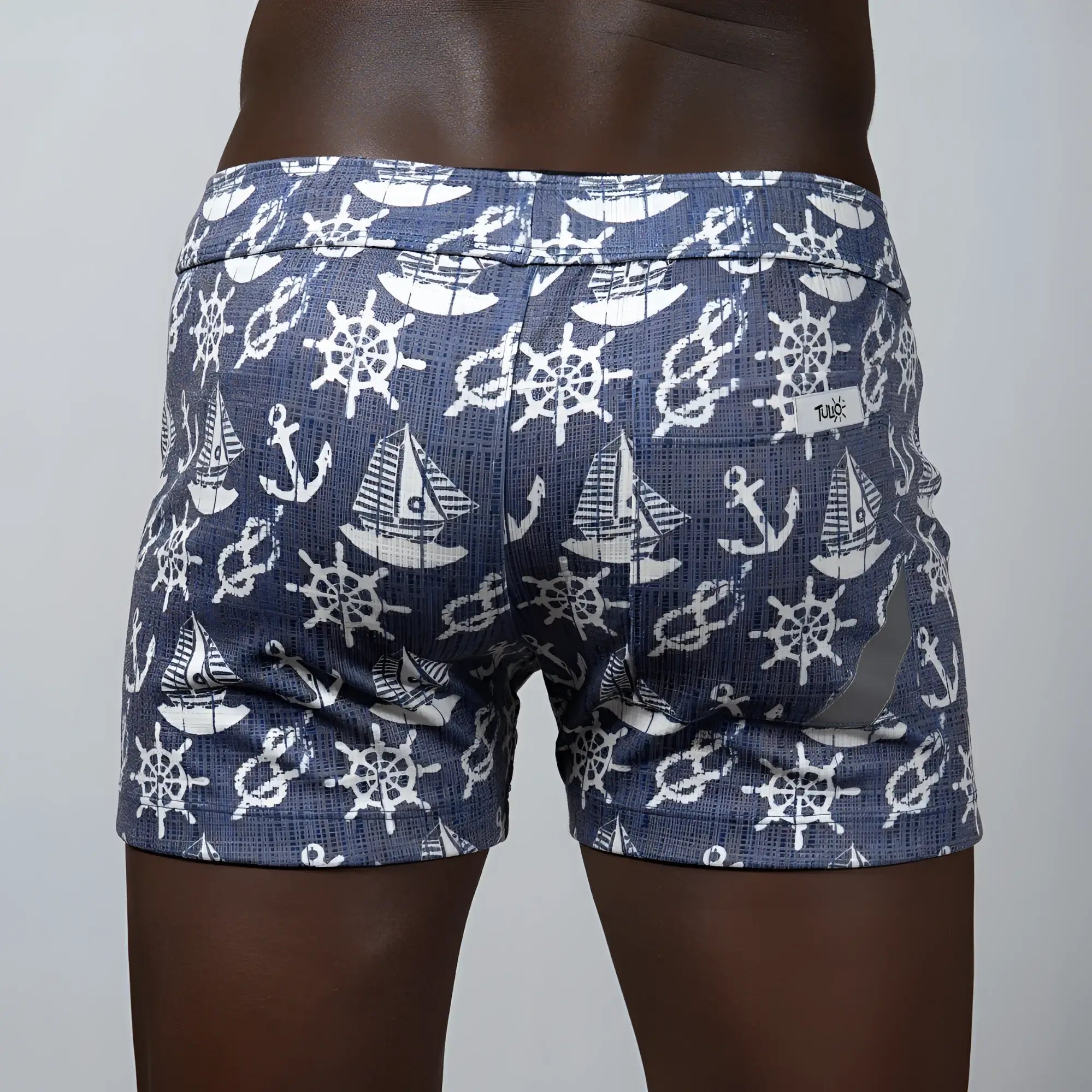 Nautical linen texture shorts in blue with white ship wheels anchors and sailboats in a repeating pattern