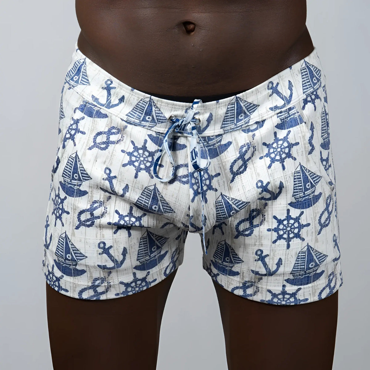 White linen texture swim trunks with blue nautical pattern of anchors sailboats and ship wheels