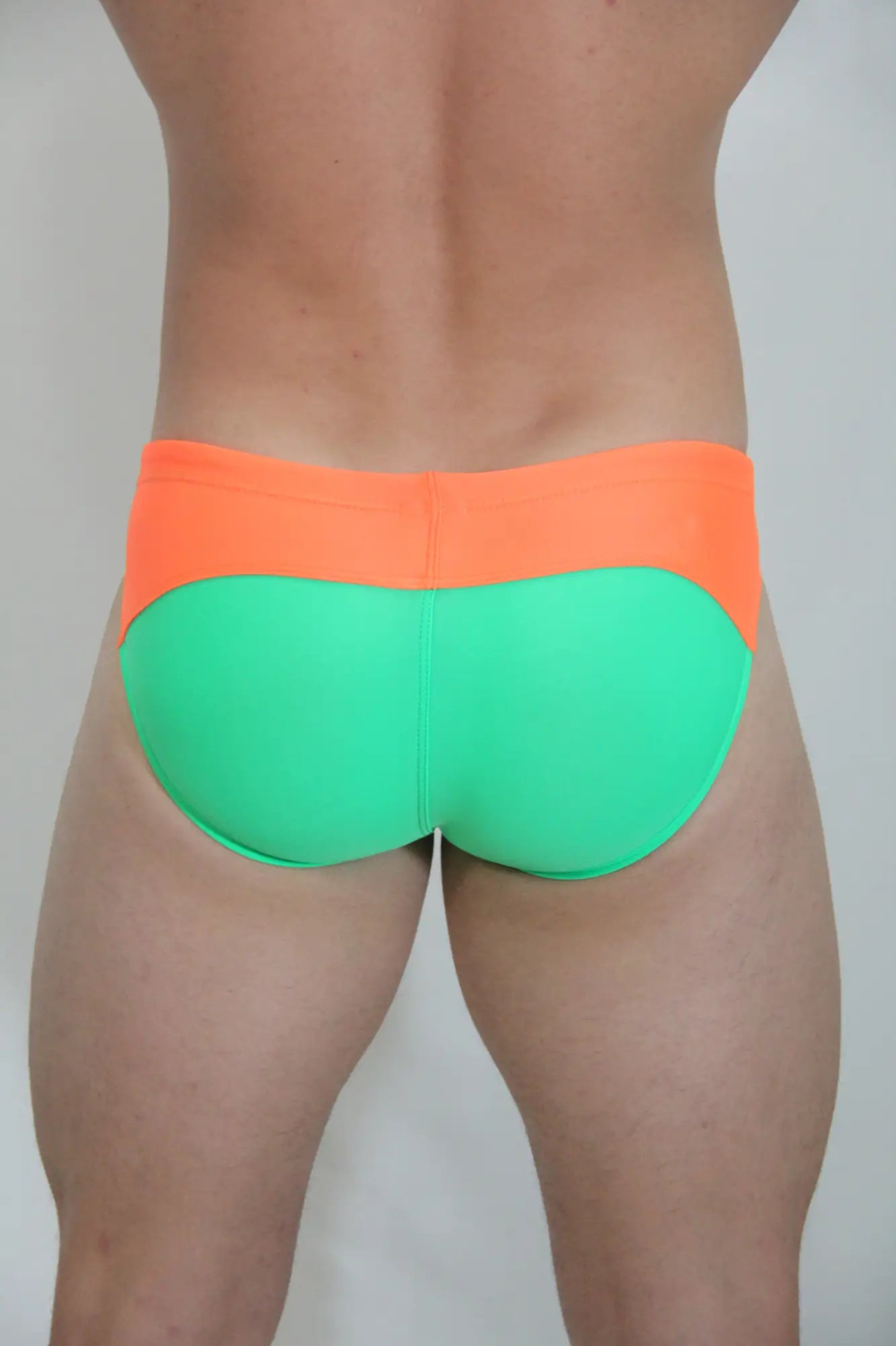 Neon curved swim brief in bright orange and neon green two-tone design for vibrant beachwear