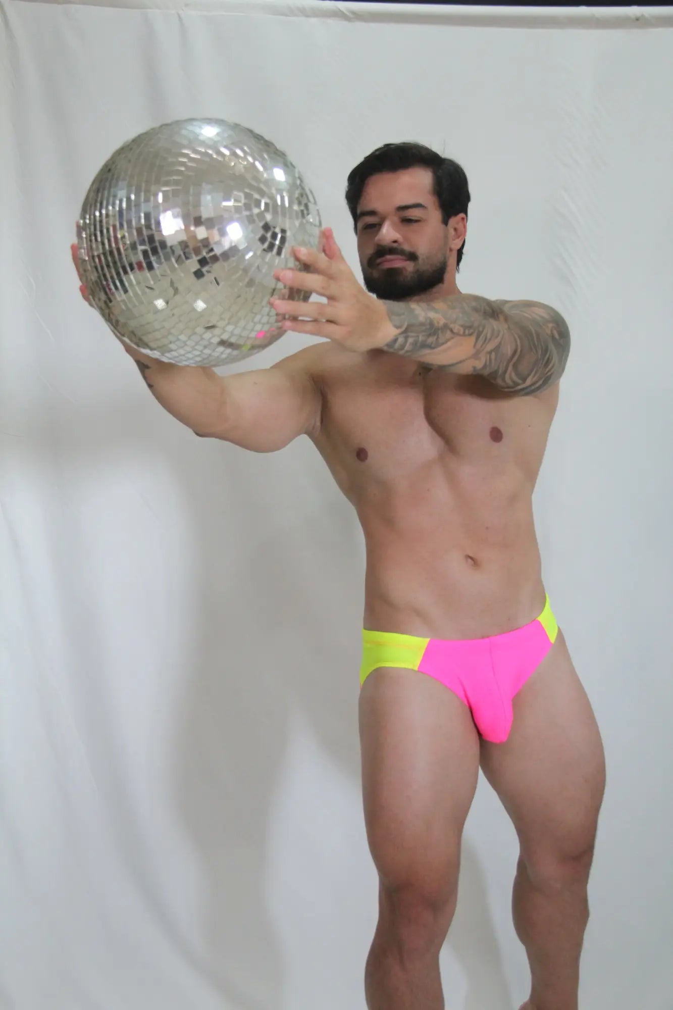 Shiny silver disco ball with mirrored facets reflecting light for neon curved swim brief ambiance