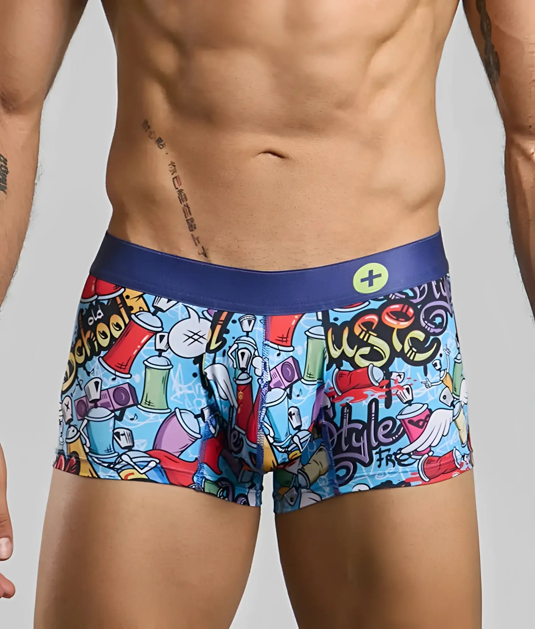 Vibrant graffiti-themed men’s boxer briefs with blue waistband and colorful spray paint cans and music notes on light blue fabric