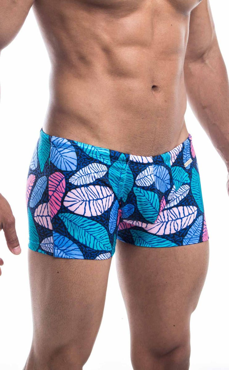 Oceanico square cut swim trunks with vibrant blue pink and teal tropical leaf pattern on a dark navy base