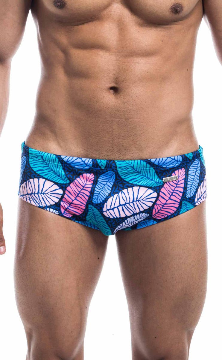 Oceanico swim brief with vibrant tropical leaf pattern in teal pink and white on a dark blue base for beachwear