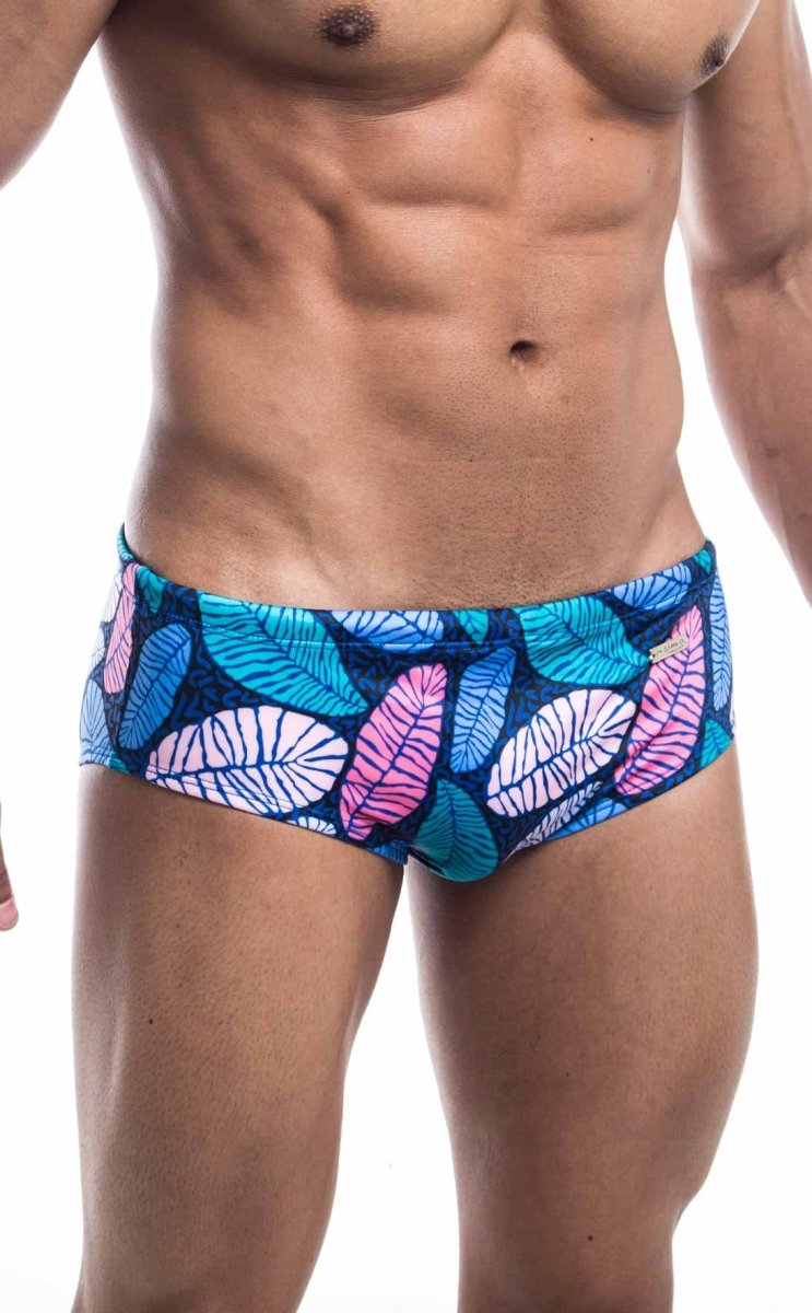Oceanico swim brief featuring vibrant tropical leaf-patterned trunks in pink teal and white on a dark blue base