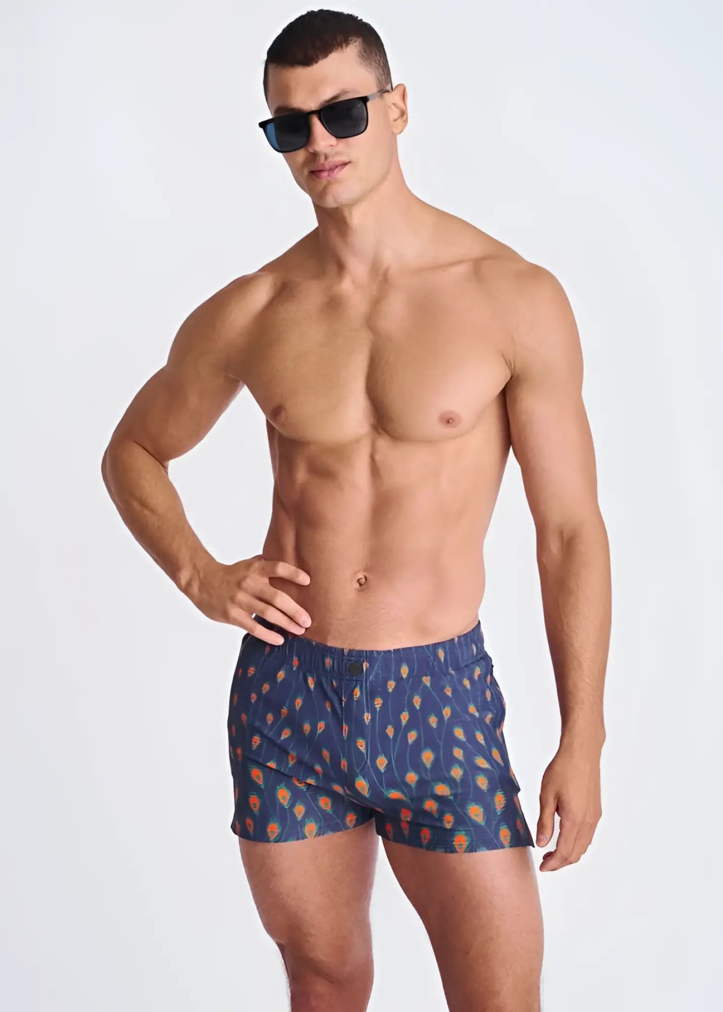 Blue seersucker swim shorts with mesh lining featuring orange and yellow peacock feather patterns