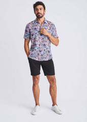 A man wearing a floral lightweight linen tencel short-sleeved shirt in shades of purple blue and pink