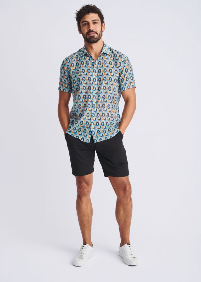 A man wearing a swirls lightweight cotton silk short sleeve shirt with blue teal and beige circular pattern