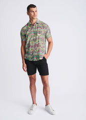 A man wearing a swirls lightweight cotton silk short-sleeved shirt with green pink and beige abstract swirl patterns