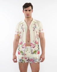 A man wearing a cream printed s s woven modal border shirt and matching shorts with vibrant floral patterns