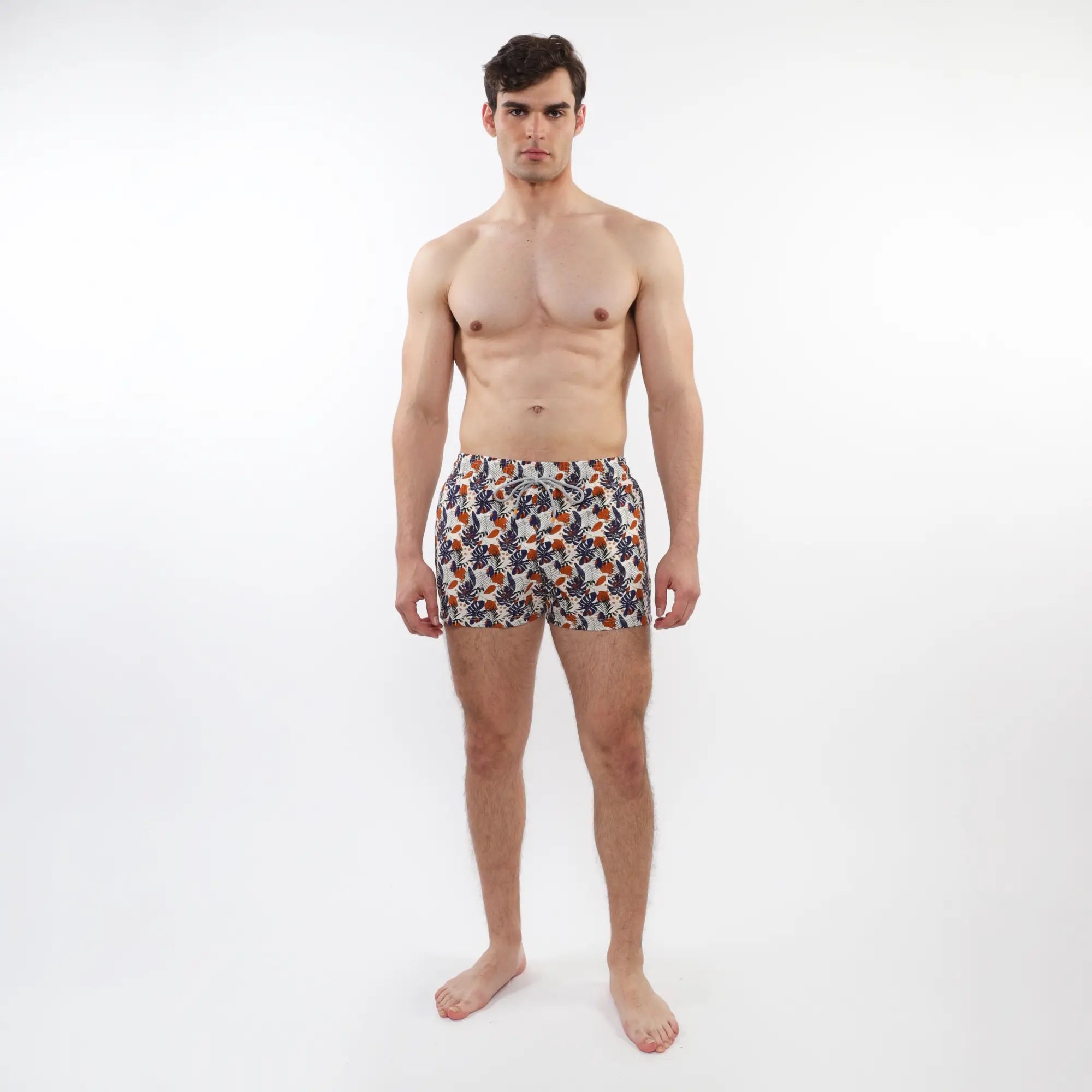 Printed swim short with mesh lining featuring vibrant orange navy blue and white tropical leaf and fruit pattern on fabric