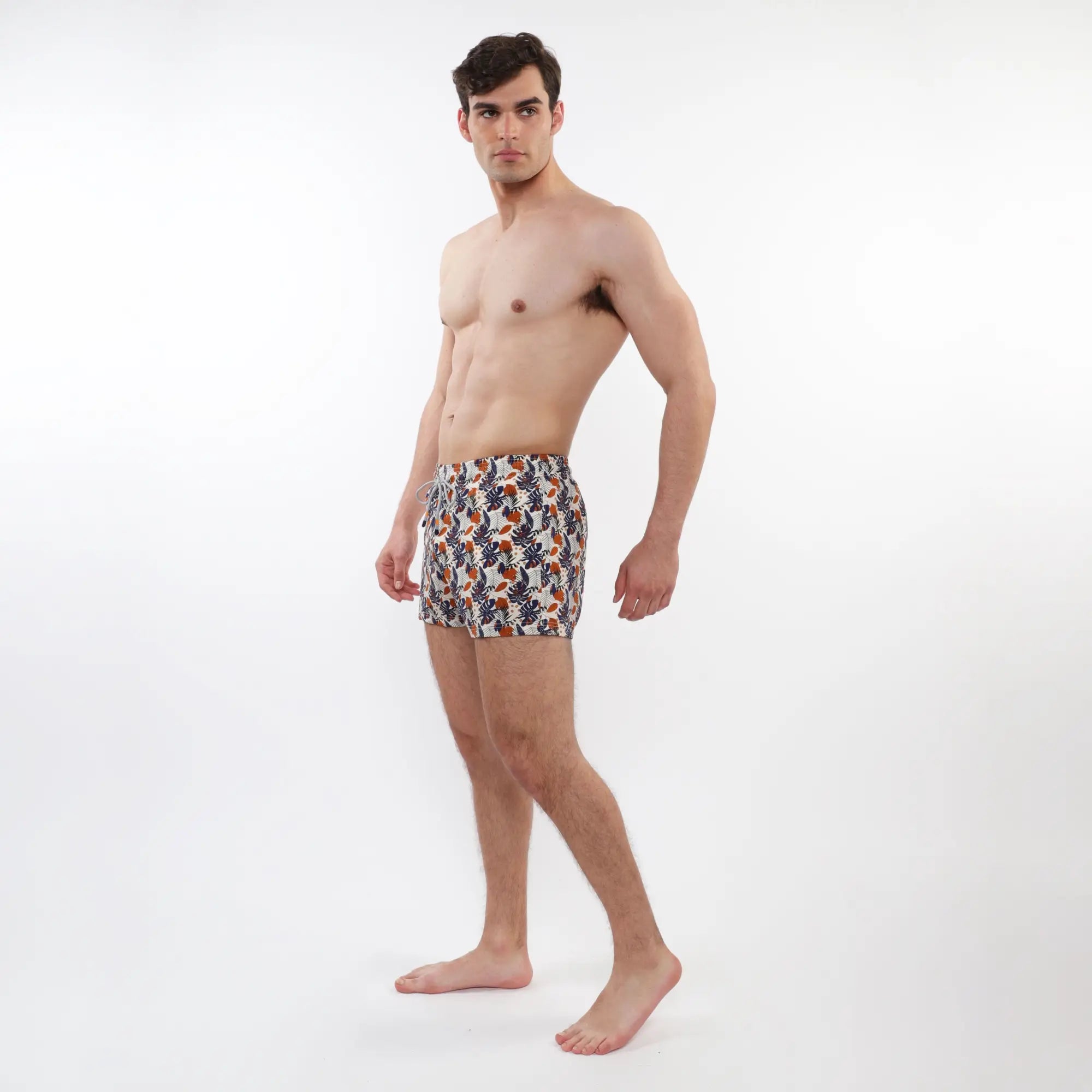 Printed swim short with mesh lining in vibrant tropical leaf pattern in orange navy blue and cream on white base