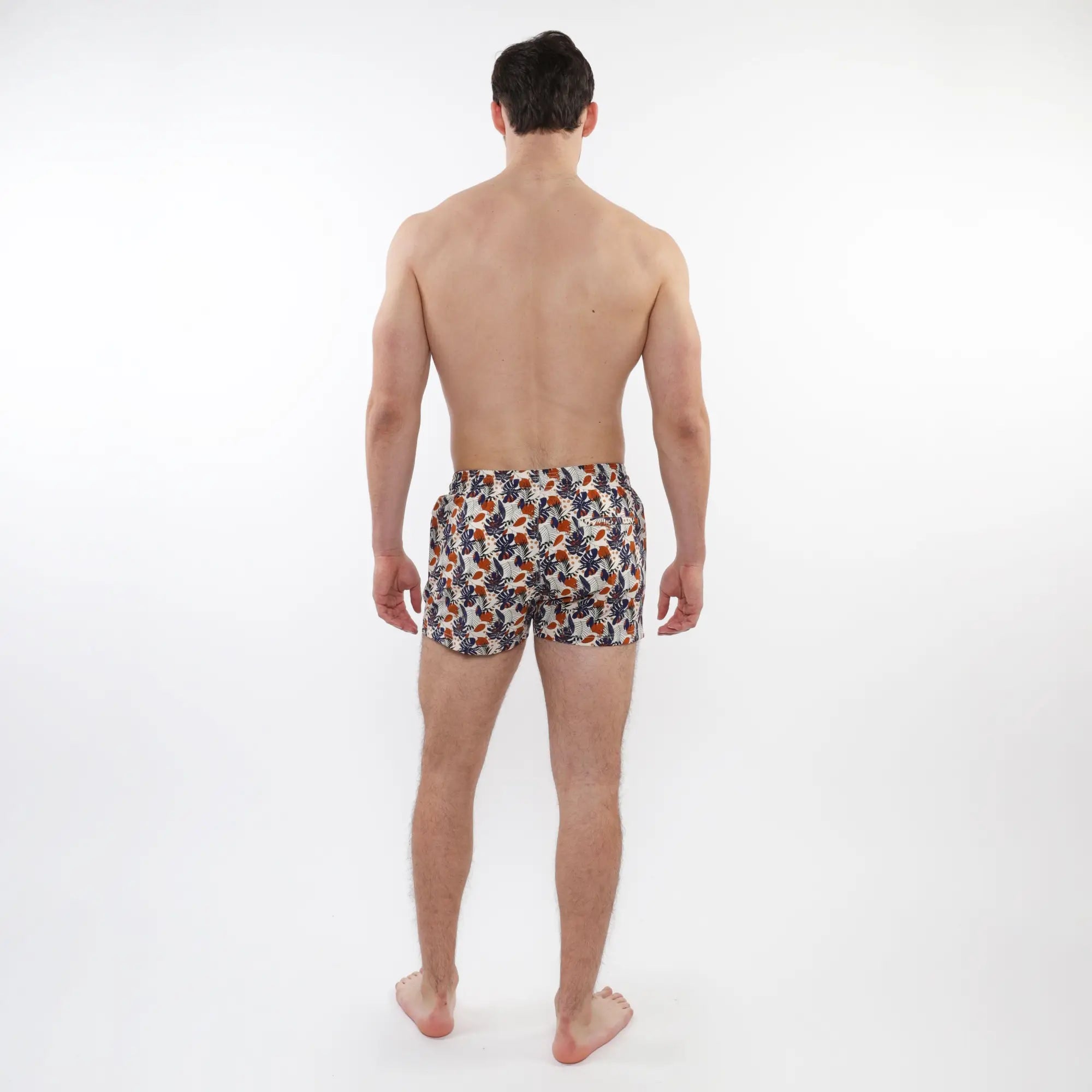 Men’s white printed swim shorts with mesh lining featuring vibrant orange and navy blue tropical leaf patterns